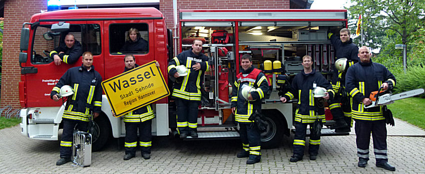 Gruppe vor Auto mit Schild